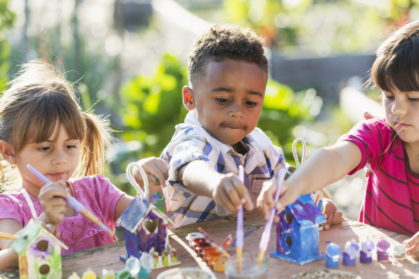 A group of children playing with toys in a garden.